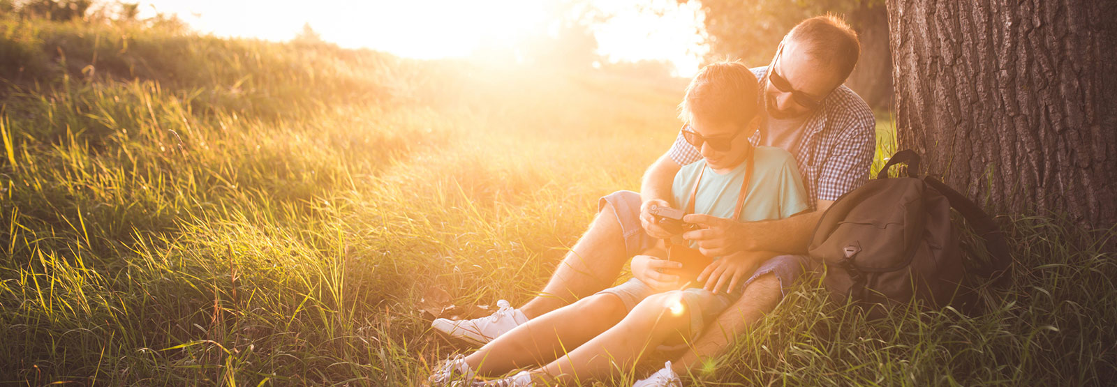 Father and child sitting next to a tree.